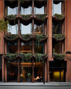 a tall building with lots of windows and plants on it