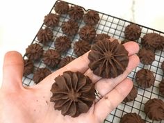 a person is holding chocolate flowers on a wire rack with cooling racks in the background