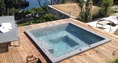 a hot tub sitting on top of a wooden deck next to a body of water