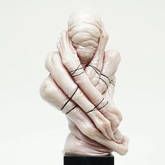 a white sculpture with black lines wrapped around it's face and hands on top of the head