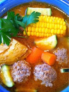 a blue bowl filled with meatballs, carrots and corn on the cob