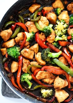 stir fry with chicken, broccoli and peppers in a pan on the stove