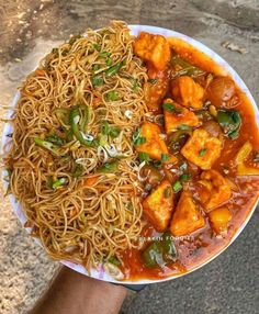 someone holding a plate of noodles and tofu