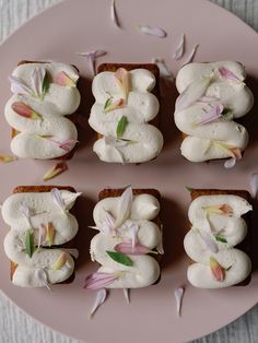 four pieces of bread with white frosting and pink flowers on them sitting on a plate