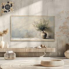 a painting hanging on the wall next to a table with vases and other items