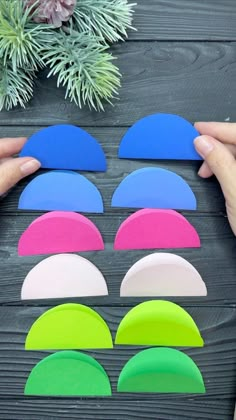 someone is holding up several pieces of paper with different colors and shapes on the table