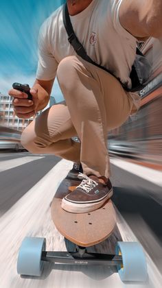 a man riding a skateboard while holding a cell phone in one hand and wearing a backpack on the other