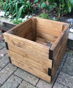 a wooden planter sitting on top of a brick floor next to a garden area