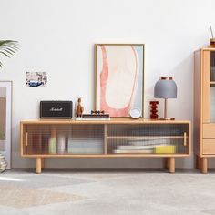 a living room with an entertainment center and sideboard on the floor next to a plant