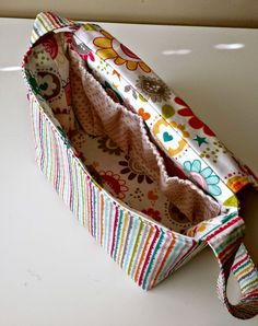 an open purse sitting on top of a white table next to a wall and window