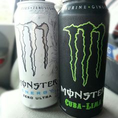 two cans of monster energy drink sitting next to each other on a counter top in a car