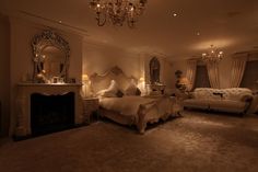 a large bedroom with a fireplace and chandelier