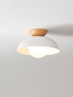 a white light hanging from the ceiling with a wooden object on it's side