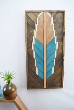 a wooden wall hanging on the side of a white wall next to a potted plant