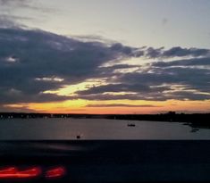 the sun is setting over some water and boats are out on the water in the distance