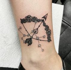 a woman's foot with an arrow and flowers tattoo on the side of her leg