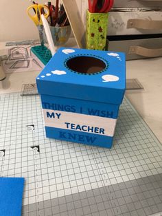 a blue box sitting on top of a table next to scissors and other crafting supplies