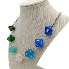 a necklace with blue and green dices hanging from it's side on a mannequin