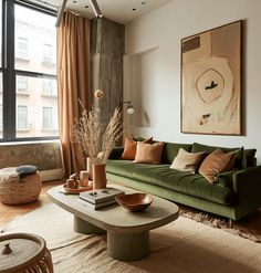 a living room with a green couch and coffee table in front of a large window