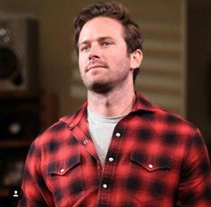 a man wearing a red and black flannel shirt looking up at something in the distance