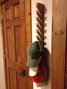 a baseball cap hanging on the side of a wooden door next to a hat rack