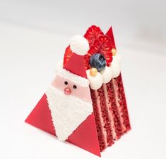 a piece of red velvet cake with santa clause on it's face and blueberries in his mouth