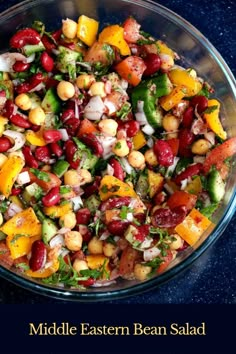 middle eastern bean salad in a glass bowl on a blue countertop with text overlay