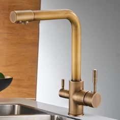 a kitchen faucet that is next to a sink with a bowl on the counter