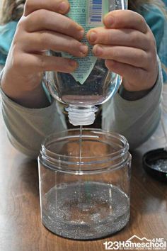 a person pouring water into a glass on top of a wooden table