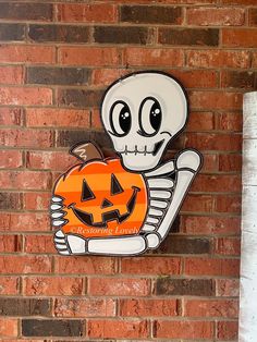 a skeleton holding a jack o lantern on a brick wall