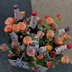 an arrangement of roses and bottles in a box on the ground next to a sidewalk