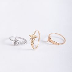 14K 18K REAL Gold Sideway Caduceus Ring, Dainty Ring, Medical Symbol Caduceus Snake Ring, Medical Jewelry Wings Ring Gift for Her 📘 D E T A I L S  * Solid Gold (real gold, no gold-filled or no gold-plated material) * Karat: 14K (585), 18K (750) * Gold color: Yellow, rose, and white * Band Thickness: 1.10 mm * Width of the Rod of Asclepius: 10.50 mm (the widest part)   Measurements may vary slightly due to handwork. 🎁 P A C K A G I N G  * All items are nicely packaged and ready to gift in jewelry boxes. * You can add the text that you want to be written on the gift card when you are ordering. ✉️ C U S T O M E R   S E R V I C E  * GoldByHeart comes from trust, happiness, and passion. We are providing prompt, polite and professional service. * We are dedicated to our customers' happiness an Rod Of Asclepius, Wings Ring, Nose Ring Jewelry, Medical Jewelry, Medical Symbols, Letter Ring, Snake Ring, White Band, Ring Dainty