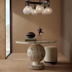 a marble table and stools in front of a wall with hanging lights above it