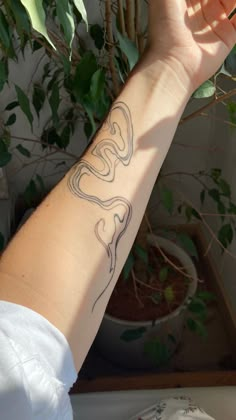 a person's arm with a tattoo on it and a plant in the background