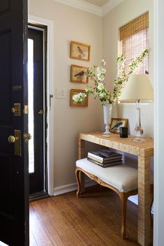 a room with a table, lamp and pictures on the wall next to a door