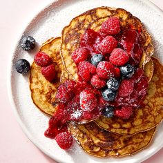 pancakes with berries and powdered sugar on a white plate