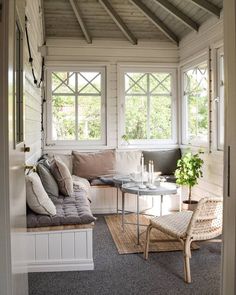 a living room filled with furniture and windows next to a table on top of a rug