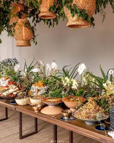 a long table filled with lots of different types of food and plants hanging from the ceiling