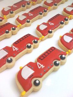 decorated cookies are arranged in the shape of cars on a white tablecloth with red and yellow trimmings