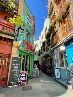 an alleyway with colorful buildings and signs on the sides, in front of a woman