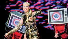 two women dressed in gold and red are on stage with an old fashioned tv behind them