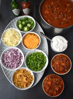 several bowls of food are arranged on a plate with spoons and condiments