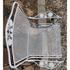 a white metal chair sitting on top of a sidewalk