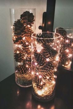 pine cones and lights in glass vases sitting on a table next to a mirror