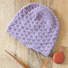 a purple crocheted hat sitting on top of a wooden floor next to an orange object