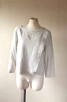 "Cream Linen Top | Cream Top | Cream Shirt | Ivory Linen Top | Ivory Top | Ivory Shirt | Cream Blouse | Ivory Blouse | Woman's Top | Blouse -Crossroad Blues - This simple yet elegant crossover asymmetric crop top is created from white cream linen mix. It has sophisticated and elegant look. The front panels are crossed over with asymmetric hemline. There is 3/4 sleeves. It has a flowy lose fit with a clean lines. The center front length for size S is 17 inches. Center back length is 21 inches. Sl Classic Neutral Tops For Layering, Elegant Neutral Tops For Layering, Cream Linen Tops For Daywear, Elegant Beige Linen Top, Fitted Linen Cream Blouse, Fitted Cream Linen Blouse, Spring Cream Linen Blouse, White Long Sleeve Top For Work, Beige Relaxed Fit Blouse For Layering