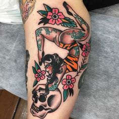 a tattoo on the leg of a woman with a skull and flowers in her hair