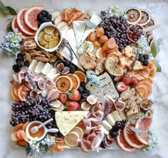 an assortment of cheeses, fruits and meats on a platter