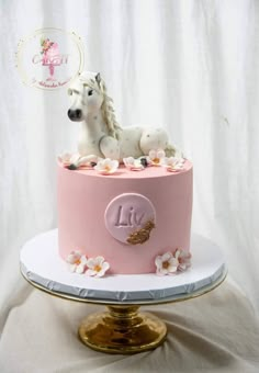 there is a pink cake with a white horse on top