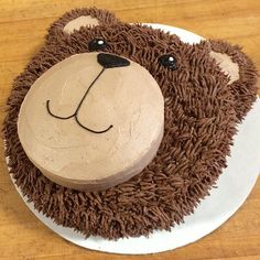 a cake shaped to look like a bear on top of a wooden table with brown frosting